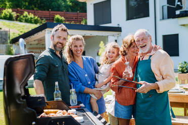 Eine Mehrgenerationenfamilie, die im Sommer während einer Gartenparty im Hinterhof grillt - HPIF10903