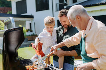 Eine Mehrgenerationenfamilie, die im Sommer während einer Gartenparty im Hinterhof grillt - HPIF10906