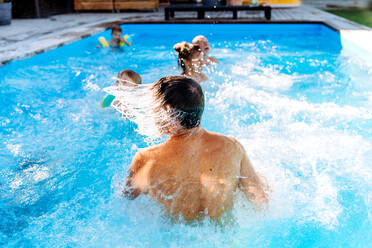 A multi generation family having fun and enjoying swimming in backyard pool. - HPIF10950