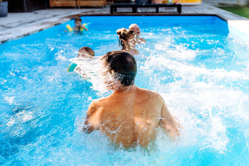 Eine Mehrgenerationen-Familie hat Spaß und genießt das Schwimmen im Pool im Hinterhof. - HPIF10950