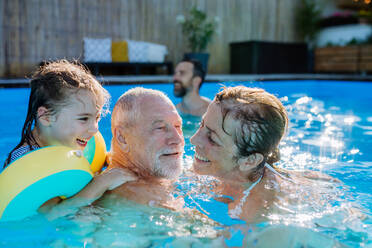 A multi generation family having fun and enjoying swimming in backyard pool. - HPIF10953