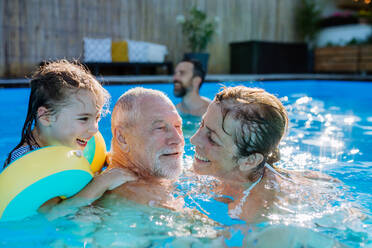 Eine Mehrgenerationen-Familie hat Spaß und genießt das Schwimmen im Pool im Hinterhof. - HPIF10953