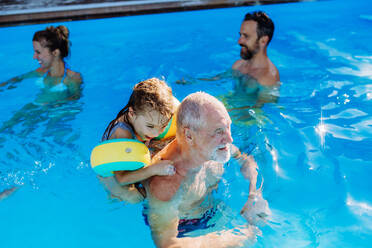 Eine Mehrgenerationen-Familie hat Spaß und genießt das Schwimmen im Pool im Hinterhof. - HPIF10954