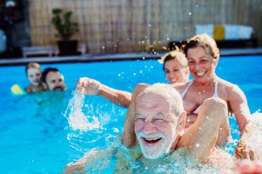 Eine Mehrgenerationen-Familie hat Spaß und genießt das Schwimmen im Pool im Hinterhof. - HPIF10955