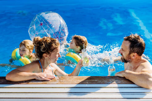 Glückliche junge Familie mit zwei Kindern, die den Sommer gemeinsam im Schwimmbad verbringen. - HPIF10958