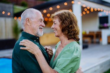 Eine ältere Frau und ein Mann tanzen zusammen in einem Garten im Sommer - HPIF10964