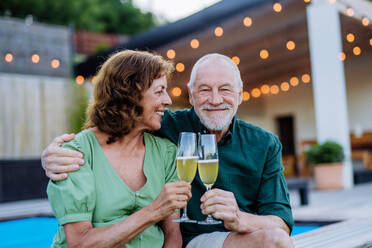 Ein Mann feiert mit seiner Frau Geburtstag und stößt mit Wein am Pool im Hinterhof an. - HPIF10970