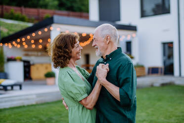 Eine ältere Frau und ein Mann tanzen zusammen in einem Garten im Sommer - HPIF10972