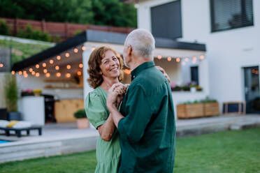 Eine ältere Frau und ein Mann tanzen zusammen in einem Garten im Sommer - HPIF10973