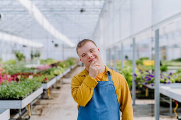 A young employee with Down syndrome working in garden centre, looking at camera. - HPIF11007