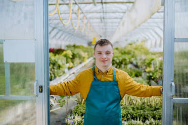 A young employee with Down syndrome working in garden centre, looking at camera. - HPIF11030