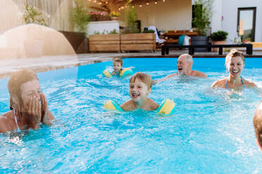 Eine Mehrgenerationen-Familie hat Spaß und genießt das Schwimmen im Pool im Hinterhof. - HPIF11059