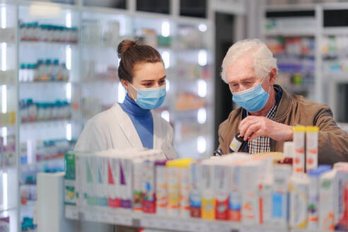 Eine junge Apothekerin hilft einem älteren Mann bei der Auswahl eines Medikaments. - HPIF11067