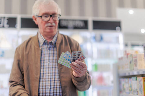 Nahaufnahme eines älteren Menschen, der in einer Apotheke Pillen in der Hand hält. - HPIF11074
