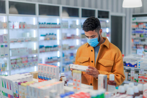 Junger multirassischer Mann bei der Auswahl eines Medikaments in einer Apotheke. - HPIF11079