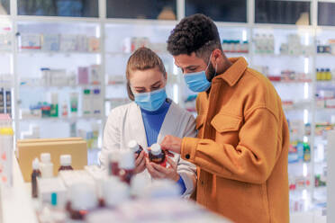 Young pharmacist helping customer to choos a medication. - HPIF11081