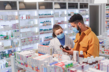 Young pharmacist helping customer to choos a medication. - HPIF11082