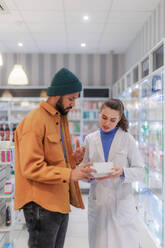 Young pharmacist helping customer to choos a medication. - HPIF11084