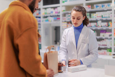 Young pharmacist selling medications to a customer. - HPIF11091
