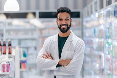 Portrait of young multiracial pharmacist looking at camera, standing in a pharmacy store. - HPIF11093