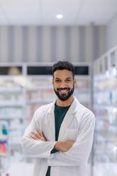 Portrait of young multiracial pharmacist looking at camera, standing in a pharmacy store. - HPIF11094