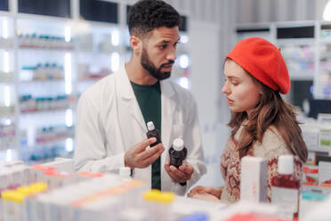 Young pharmacist helping customer to choos a medication. - HPIF11096