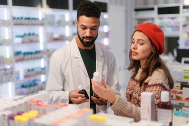 Young pharmacist helping customer to choos a medication. - HPIF11097