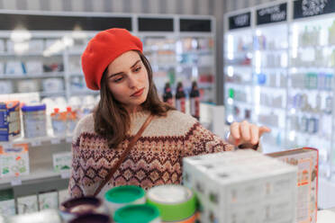 Junge Frau bei der Auswahl eines Medikaments in einer Apotheke. - HPIF11099