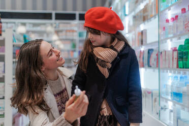 Junge Frau mit ihrer Tochter bei der Auswahl eines Medikaments in einem Apothekengeschäft. - HPIF11104