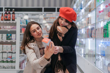 Junge Frau mit ihrer Tochter bei der Auswahl eines Medikaments in einem Apothekengeschäft. - HPIF11105