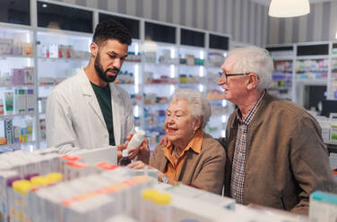 Young pharmacist helping senior couple to choos a medication. - HPIF11108