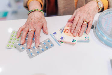 Nahaufnahme einer älteren Frau, die in einer Apotheke für Tabletten bezahlt. - HPIF11112