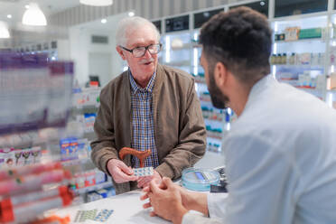 Junge Apothekerin, die einem Kunden erklärt, wie man ein Medikament dosiert. - HPIF11114