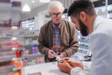 Young pharmacist explaining to customer how to dosing a medication. - HPIF11115
