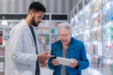 Junge Apothekerin hilft einer älteren Frau bei der Auswahl eines Medikaments. - HPIF11118