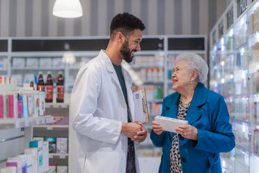 Junge Apothekerin hilft einer älteren Frau bei der Auswahl eines Medikaments. - HPIF11119