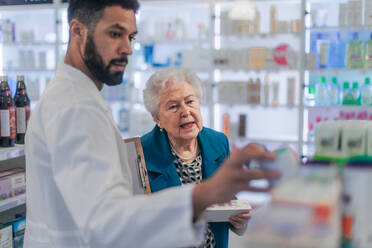 Young pharmacist helping senior woman to choos a medication. - HPIF11120