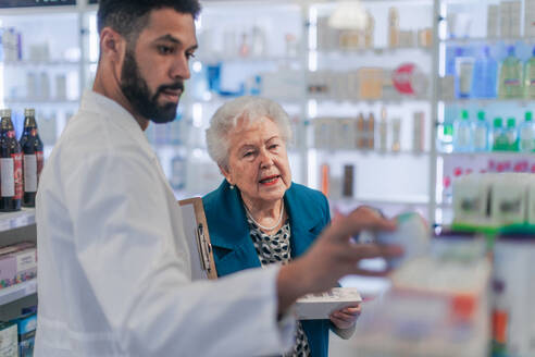 Junge Apothekerin hilft einer älteren Frau bei der Auswahl eines Medikaments. - HPIF11120
