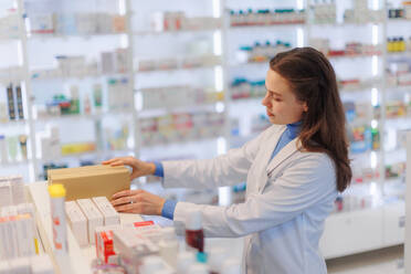 Young pharmacist checking medicine stock in a pharmacy. - HPIF11132