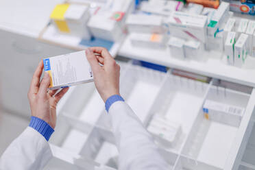 Close-up of pharmacist holding medicines in pharmacy. - HPIF11139