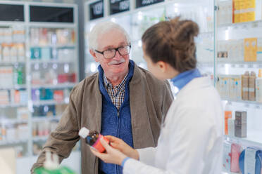 Young pharmacist helping senior man to choos a medication. - HPIF11153