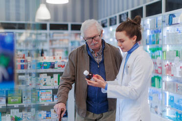 Young pharmacist helping senior man to choos a medication. - HPIF11154