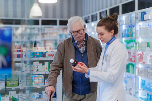 Eine junge Apothekerin hilft einem älteren Mann bei der Auswahl eines Medikaments. - HPIF11154