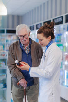 Eine junge Apothekerin hilft einem älteren Mann bei der Auswahl eines Medikaments. - HPIF11155