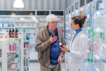 Portrait of young pharmacist and senior man in a pharmacy store. - HPIF11157