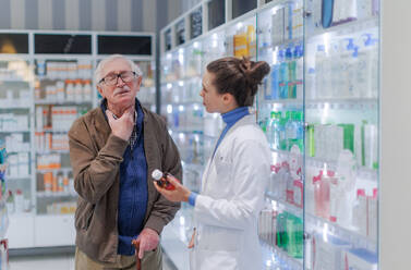 Eine junge Apothekerin hilft einem älteren Mann bei der Auswahl eines Medikaments. - HPIF11158