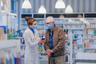 Eine junge Apothekerin hilft einem älteren Mann bei der Auswahl eines Medikaments. - HPIF11160