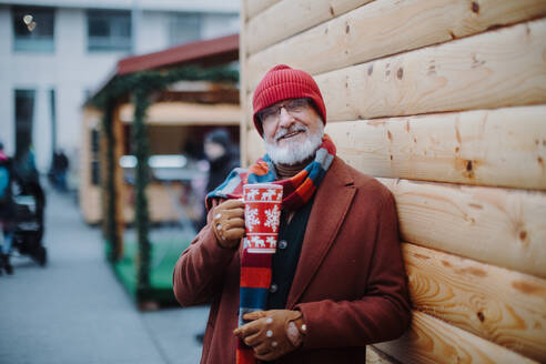 Glücklicher älterer Mann genießt den Weihnachtsmarkt im Freien und trinkt Punsch. - HPIF11165