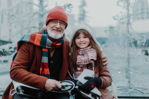Porträt von Großvater und Enkelin im Winter auf einer Eislaufbahn im Freien. - HPIF11167