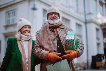 Happy senior couple enjoying outdoor christmas market, buying gifts. - HPIF11177